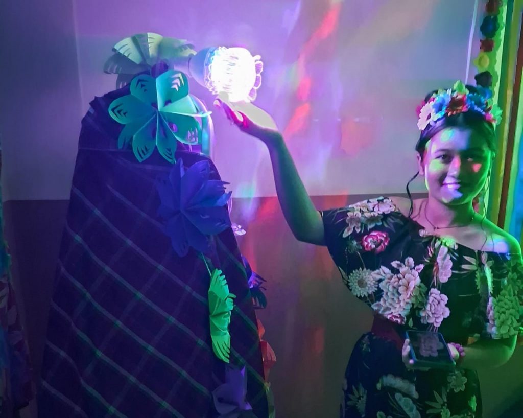 Estudante "Frida" na sala sensorial com música, flores e cores